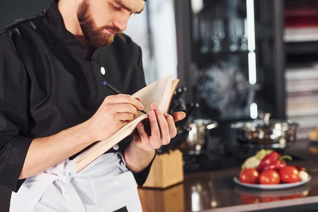 Kucharz piszący notatki w kuchni